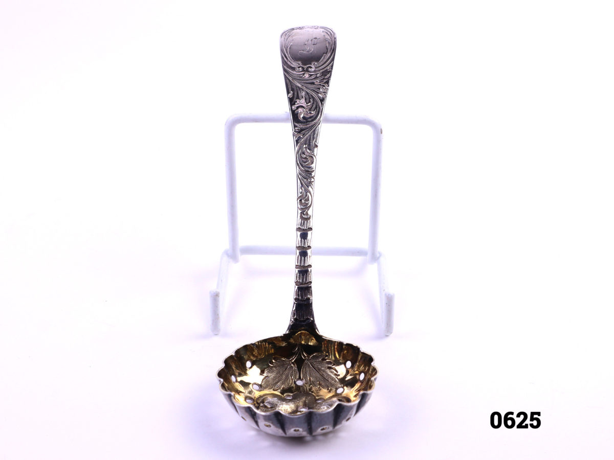Antique silver strainer spoon with gilt bowl decorated with fruit Traditionally used to strain fruit especially berries c1829 London assayed Bowl measures 43mm in diameter and 13mm deep Photo of front of spoon from a raised angle showing partial interior of bowl