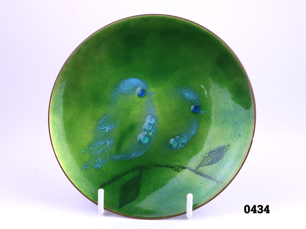 Mid century enamel on copper small plate with two birds on a branch by American enamel artist Judith Wedemeier (Pre-marriage to Norman Howard Brumm) Background colour in an iridescent like shades of green with birds accentuated in pale blue Signed Wedemeier USA to base Measures 125mm in diameter