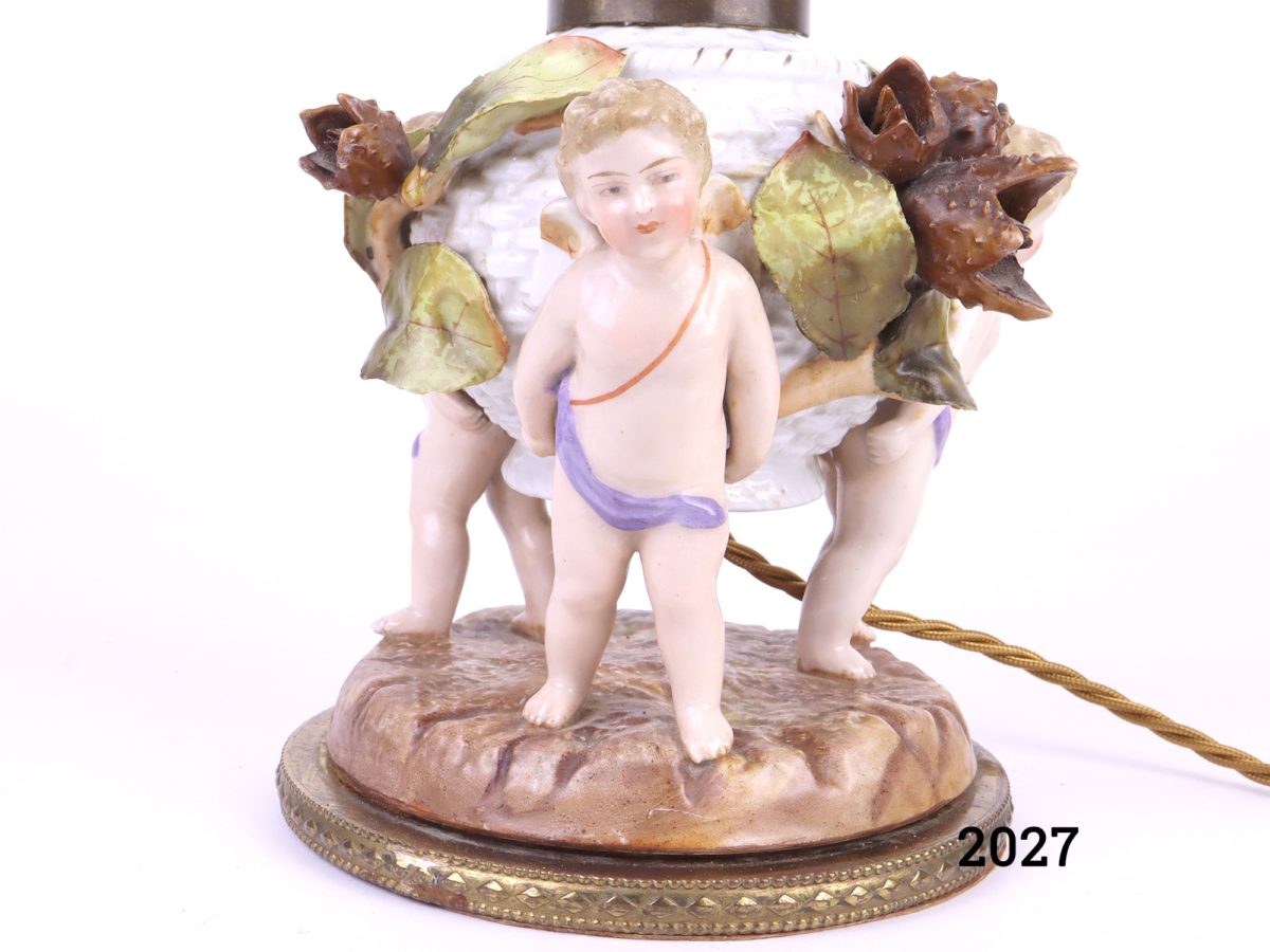 Antique pair of Continental porcelain lamps decorated with 3 winged cherubs holding a basket with leaves & beech nut seed pods Measures 140mm in diameter at base Close up of cherub detail