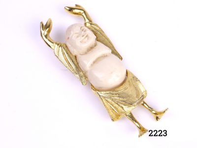 Buddha of Chance brooch by David Grau Signed DAG Made in Spain (Buddha has raised arms and shorts and legs in gilt metal with a cream plastic face and body Brooch measures 70mm long by 30mm wide and weighs 28.1g Photo of front of brooch