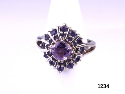 925 Sterling silver ring with princess cut amethyst stone to the centre surrounded by 12 small round lazulite stones. Size N / 6.75. Main photo showing front view of ring displayed on a stand.