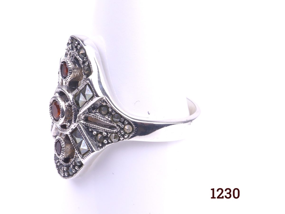 Silver and garnet ring 925 Sterling silver ring set with three garnets and marcasite in an Art Deco style Size R / 8.5 Ring front measures 25mm by 22mm Photo showing side view of ring on display stand
