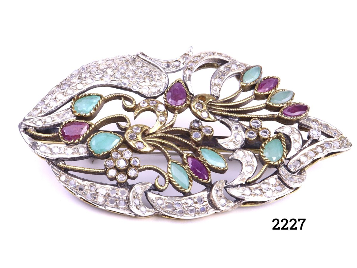 c1940s Sterling silver brooch with industrial rubies and emeralds nestled in gilt silver branches and surrounded with crystal glass. Hallmarked 925 for sterling silver (Repair to clasp & 1 small crystal missing) Measures 70mm long by 40mm wide and 15mm deep Weight 23.2g Main photo of front of brooch