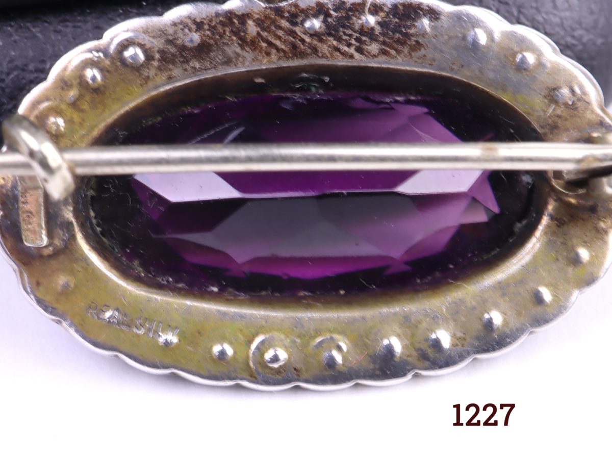 Edwardian silver petite oval brooch with amethyst coloured stone surrounded with seed pearls Close up photo of the back of brooch