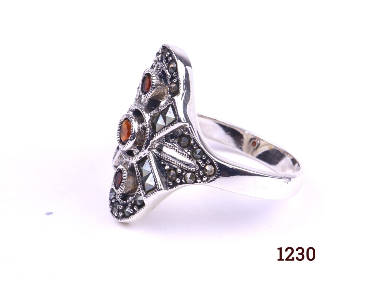 Silver and garnet ring 925 Sterling silver ring set with three garnets and marcasite in an Art Deco style Size R / 8.5 Ring front measures 25mm by 22mm Photo showing side of ring on flat surface