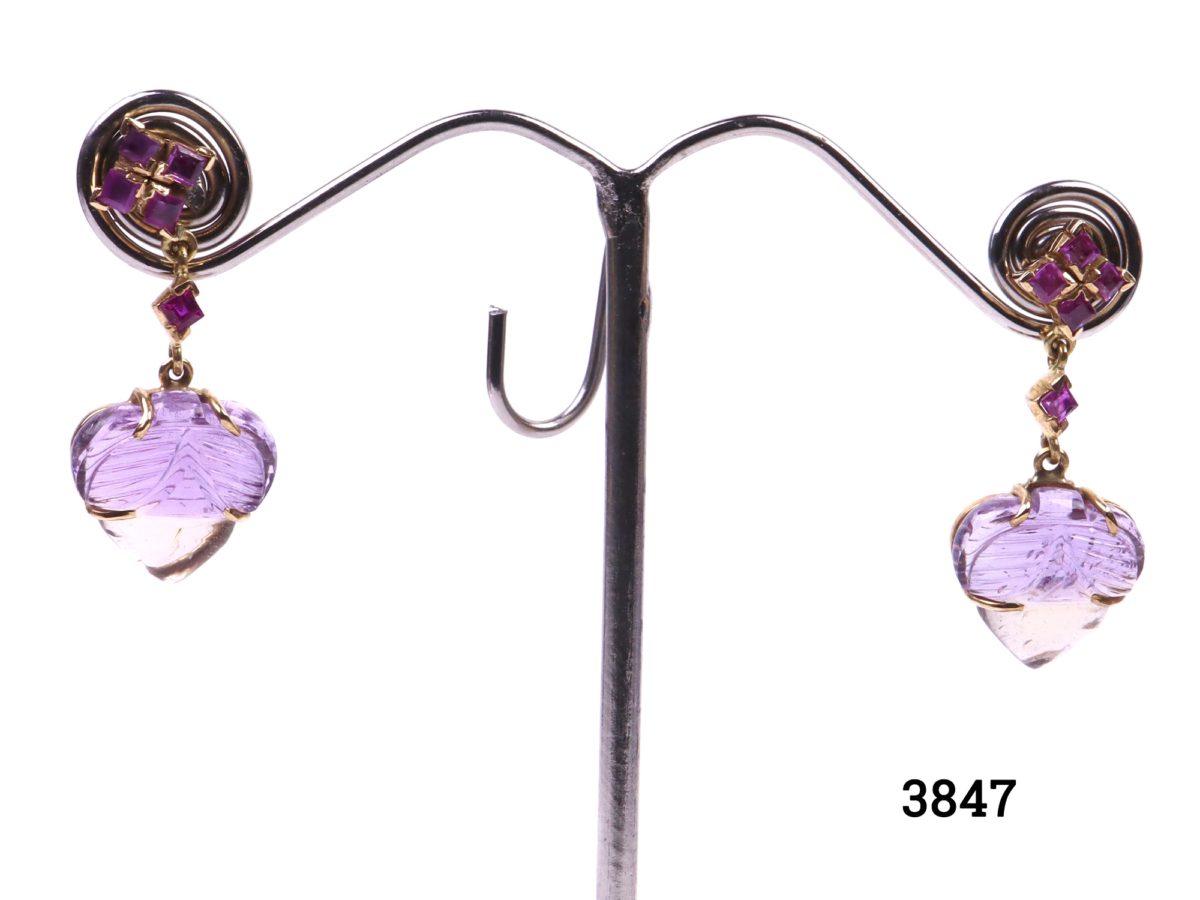 Ametrine and ruby earrings set in 18 carat gold (Ametrine is a variety of quartz with a mixture of amethyst and citrine). Drop length 35mm, 15mm at widest point and approximately 5mm in depth. Main photo showing earrings on a display stand.