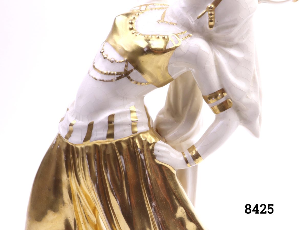 Art Deco porcelain figure of a Bedouin dancer with a tambourine in hand-painted gold hi-lights Made in Sitzendorf, Germany (Restoration work to tambourine, some crazing & cracking and wear to gold) Close up of the midriff detail