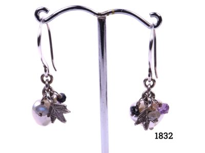 Azuni sterling silver earrings decorated with charms consisting of pearlised heart, silver leaf and crystal beads in different colours. Main photo of earrings displayed on a stand