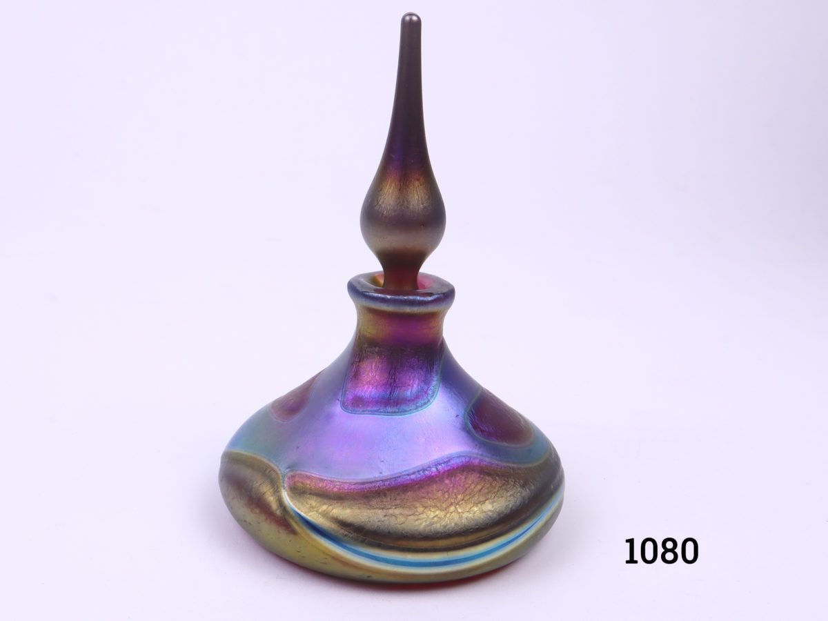 Okra Studio Art Glass scent bottle in shades of iridescent blue, purple and gold Signed to the base Measures 75mm in diameter at base Main photo of bottle with stopper on