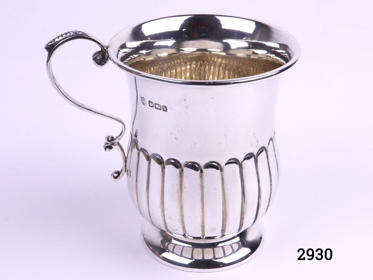 Small sterling silver mug with gilt interior c1920 Sheffield assayed made by James Deakin and Sons Photo looking down at mug from a slight raised angle with handle to the left and showing gilt interior