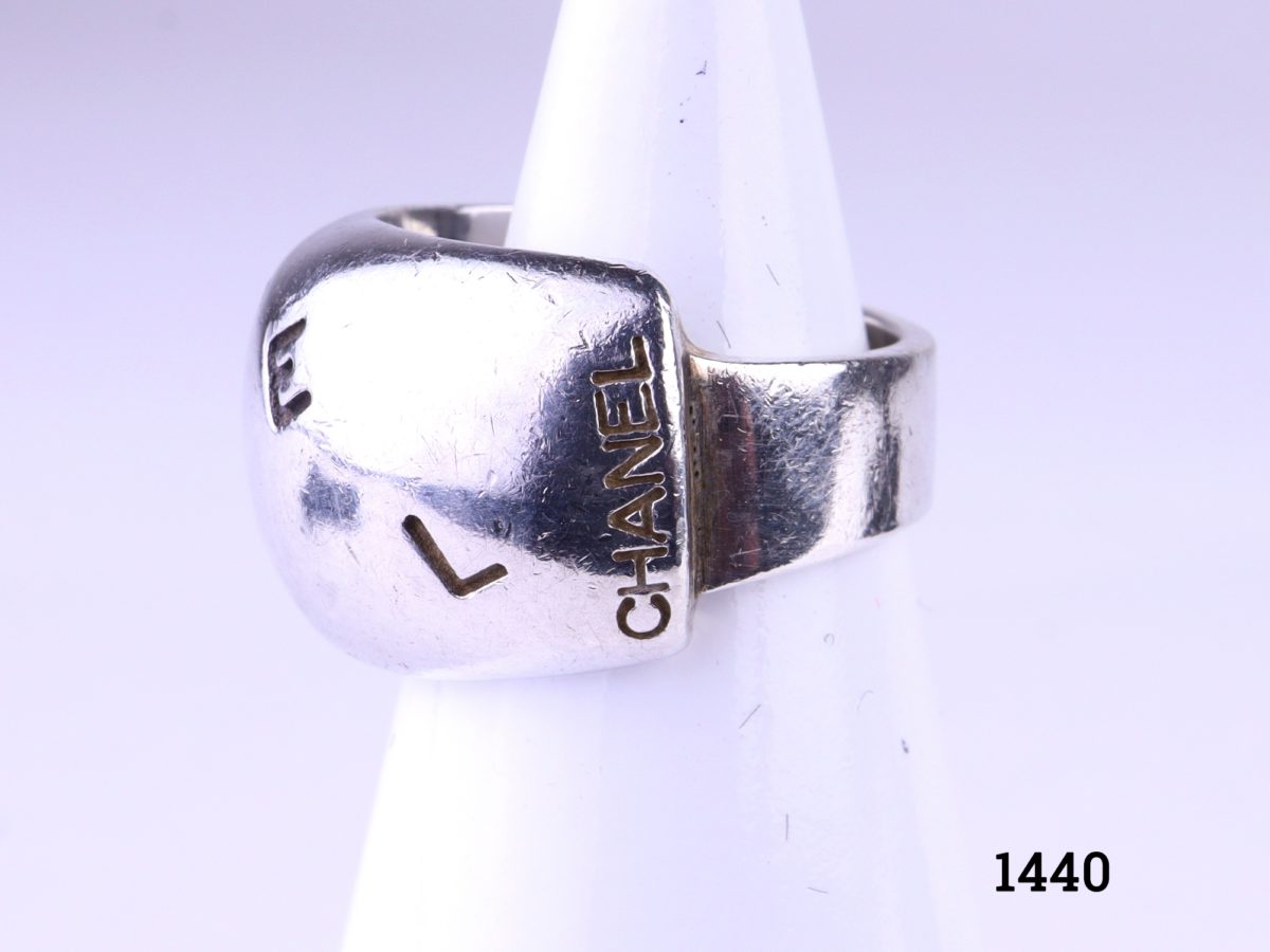 925 Sterling silver chunky Chanel ring. Width at front 11mm. Comes with Chanel pouch.  A very small size H / 3.75 Photo showing front of ring displayed on stand with some Chanel letters showing Photo showing the Chanel name in full on the right side of ring