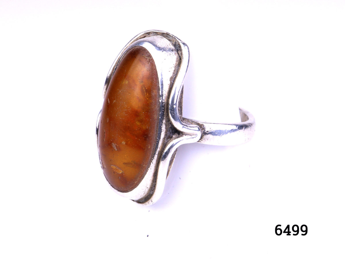 925 Silver ring with Baltic amber stone. Hallmarked on outerband of ring. Made in Gdansk Poland. Size O.5 / 7.5 Ring front measures 30mm x 17mm Photo of ring from a side angle