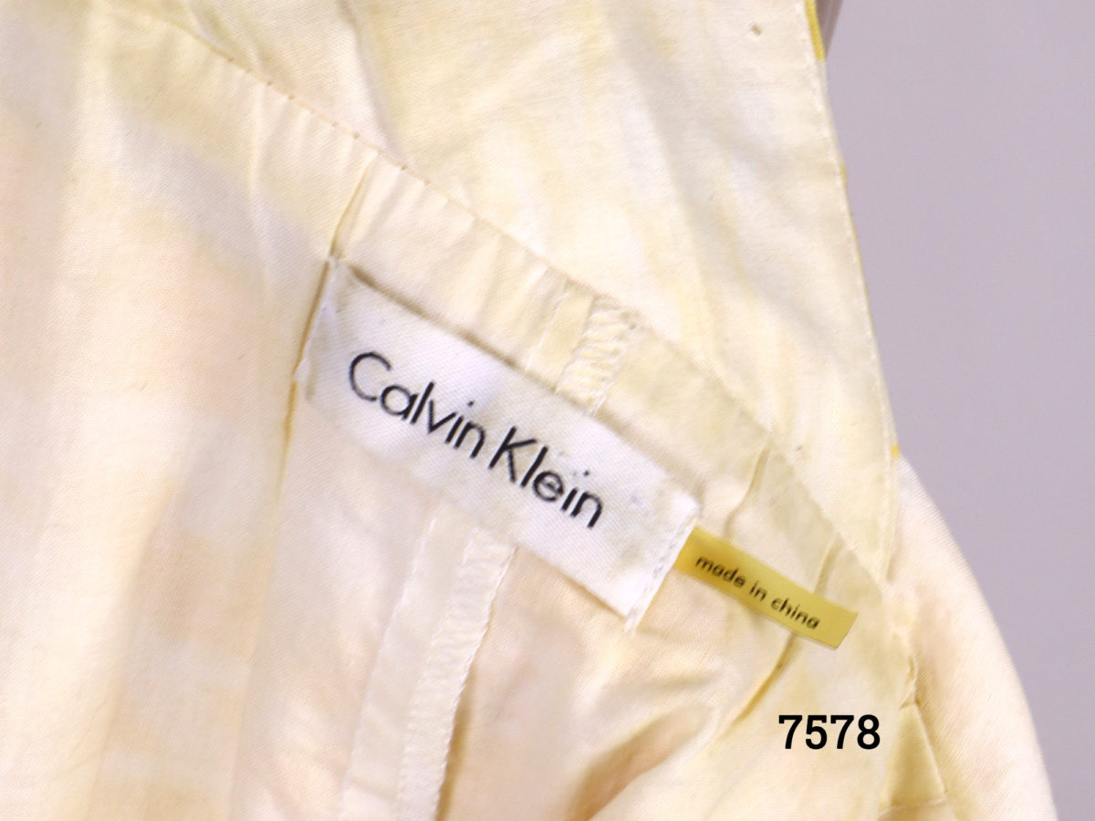 Calvin Klein strap dress in yellow and white cotton. Side zip fastening. Size 10 Close up photo of Calvin Klein Made in China label