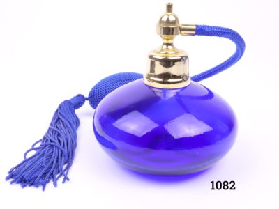 Modern cobalt blue glass perfume bottle with atomiser in matching cobalt blue with tassels. Measures 90mm in diameter Main photo showing perfume bottle with atomiser sitting behind