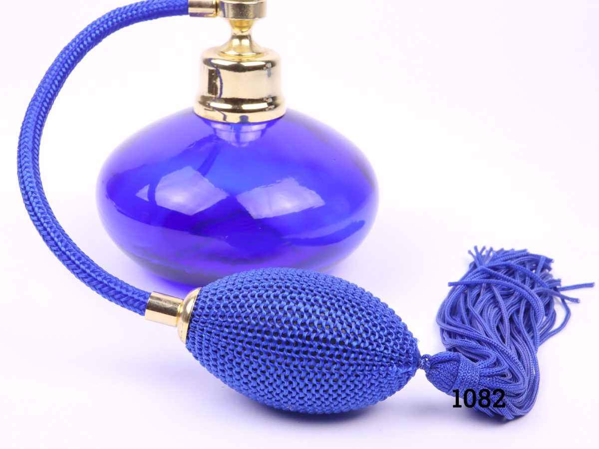 Modern cobalt blue glass perfume bottle with atomiser in matching cobalt blue with tassels. Measures 90mm in diameter Close up photo of the tassel