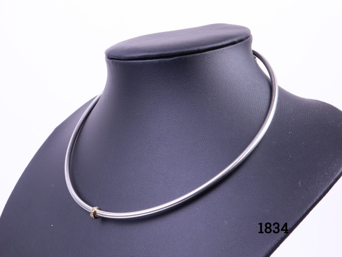 Diana Porter choker style necklace in hallmarked sterling silver with a 22 carat gold spirit bead charm Necklace width opening 127mm and depth 120mm Photo of choker displayed on stand seen from a sideways angle Main photo showing the choker on display stand with gold charm to the front