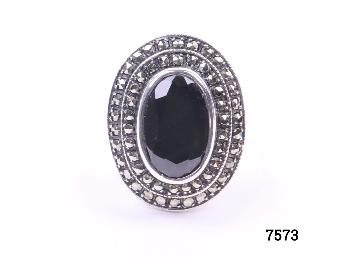 925 Sterling silver ring with black onyx and marcasite. Size Q / 8. Ring frontage measures 23mm by 20mm Photo of ring on a flat surface front view
