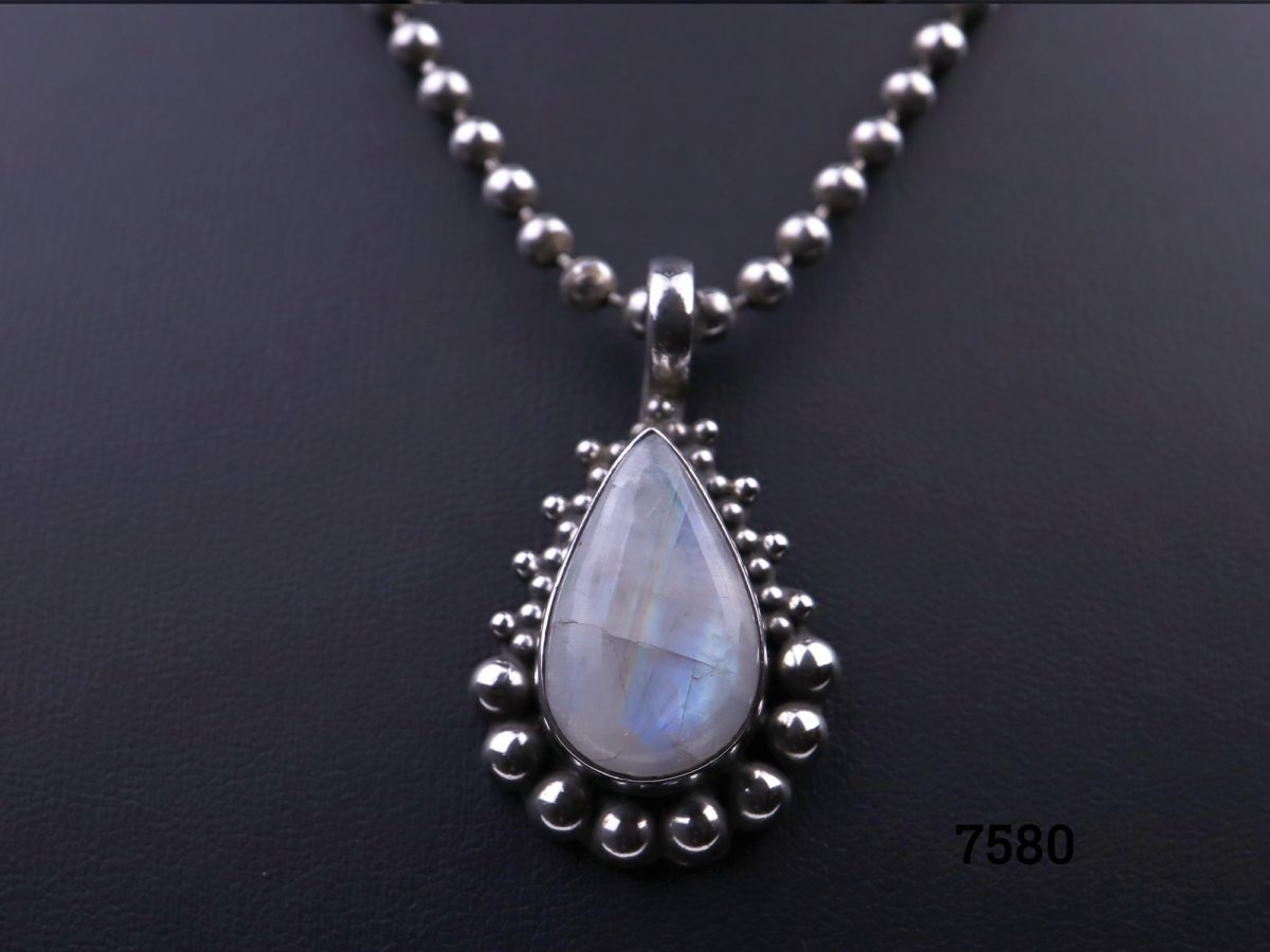 Rainbow or blue moonstone teardrop pendant set on 925 sterling silver with ball chain matching the frame of the pendant Pendant drop length 35mm and weighs 10.2g Close up photo of the pendant showing the flecks of blue hues in the stone