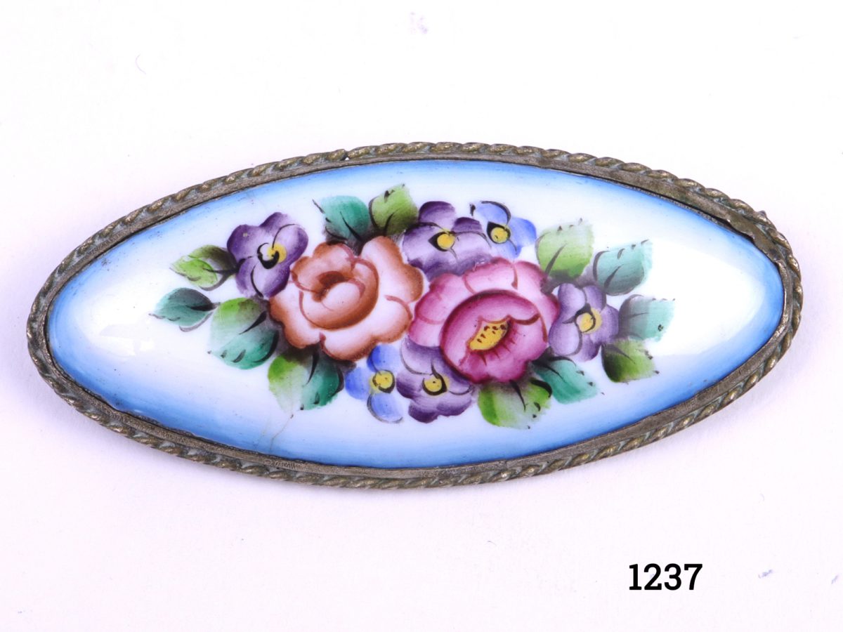Vintage hand-painted brooch on brass coloured mount with hand-painted multi-coloured enamel flowers Photo showing the front of the brooch displaying the pale blue background with multiple coloured flowers to the centre