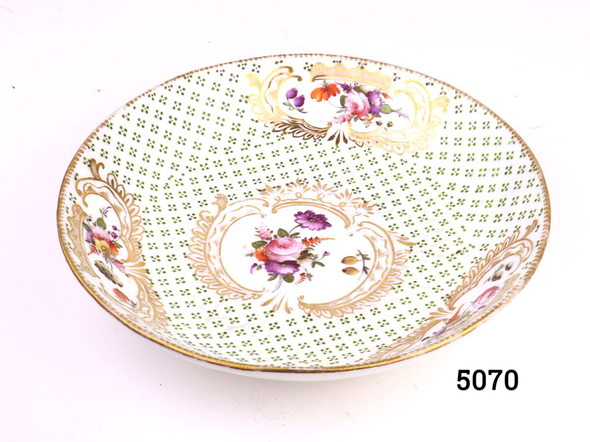 Antique early Coalport shallow dish hand-painted with flowers and gilt with debossed green pattern throughout. Measures 100mm in diameter at base and 170mm across the top. Photo looking into the decorative interior of bowl