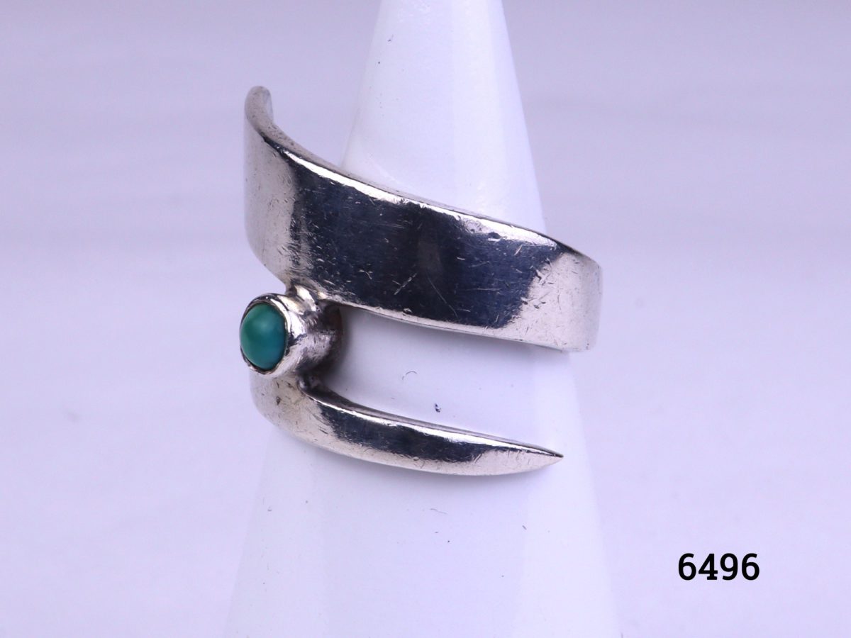 Modernist style vintage silver ring. Vintage sterling silver ring in an asymmetrical twist design with single small turquoise stone accent Size M.5 / 6.5 Photo of ring on display stand from a side angle