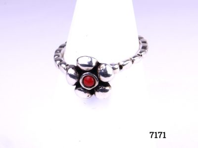 Silver flower ring with a small red stone to the centre (possibly coral) Hallmarked 925 for sterling silver Size O / 7.25 Main photo of ring from front displayed on stand