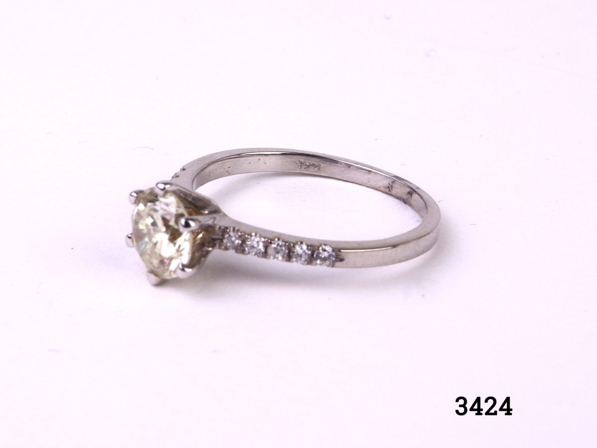 Vintage 1 carat round cut diamond set on new 14karat white gold ring with 12 small vintage diamonds set in the shoulders (6 to each shoulder). SI1 clarity diamond with E to F colour. Gemological Institute of Europe (G.I.E) certified. Box included. Size L.5 / 6 Weight 1.8 grammes Another photo of ring on a flat surface shown from a side angle