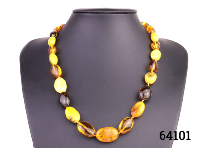Vintage necklace with alternating beads of egg yolk and cognac amber with a sterling silver clasp. Largest bead measures 24mm long by 12mm Main photo showing necklace from the front displayed on a stand