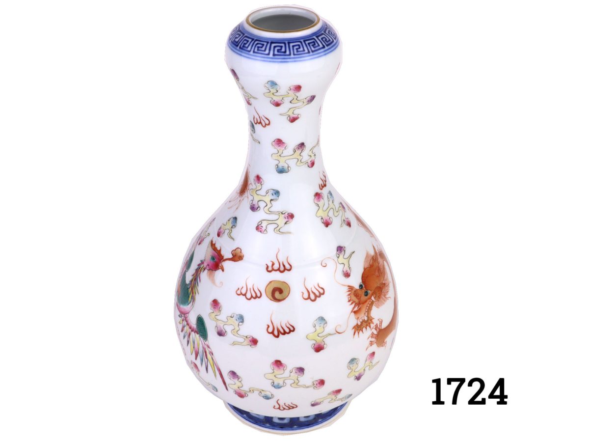 A vintage Chinese bulbous thin necked vase on green, blue and white ground. Hand-painted with a golden red dragon to one side and green and pink phoenix on the other symbolising success and prosperity. Stamped to the base. Measures 80mm in diameter at base and 30mm in diameter at opening at top. Photo of vase from a slight raised angle showing the pattern in between the dragon and the phoenix
