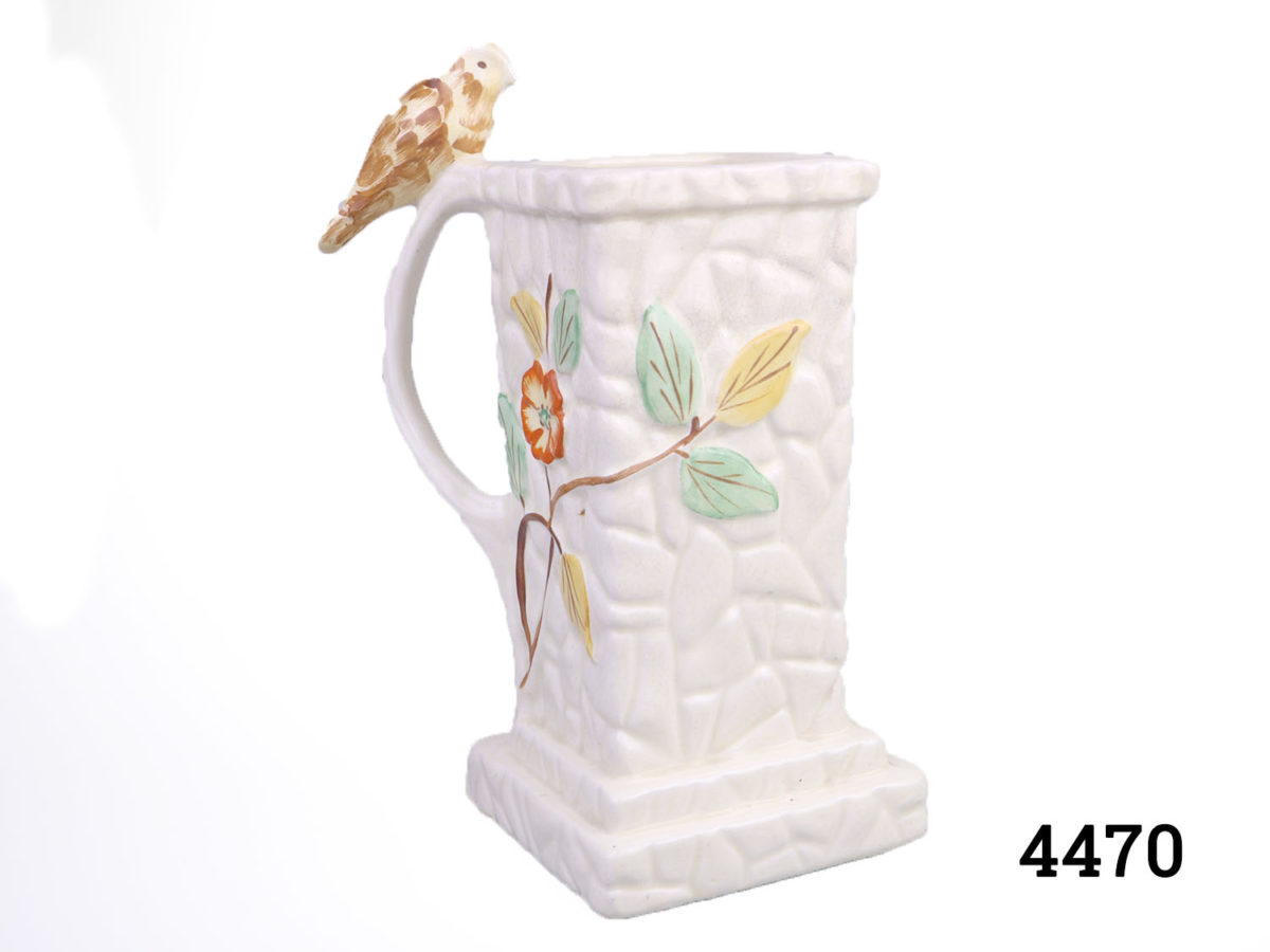 1930s Wintertons hand-painted jug with bird figurine on handle. Base measures 115mm square Photo of jug at an angle showing 2 sides of the square shape and bird on handle to the left