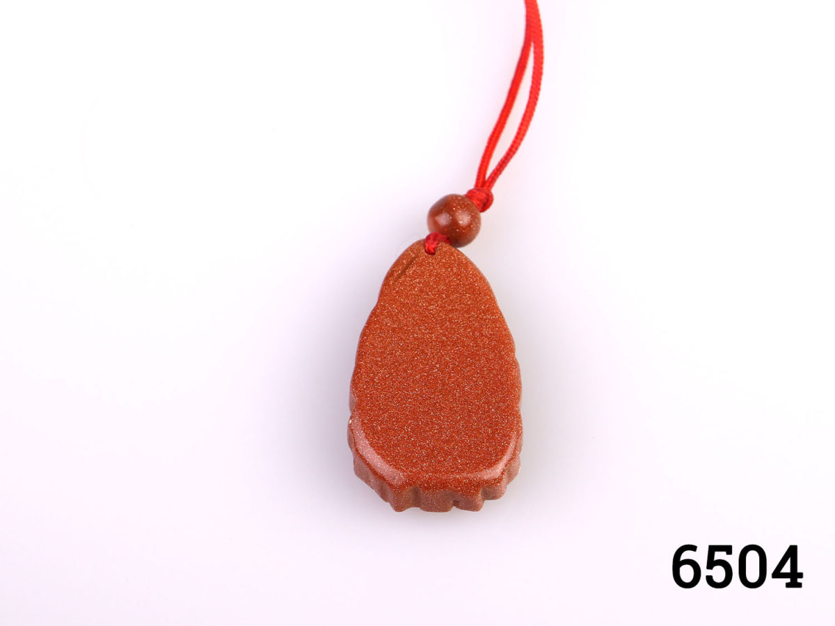 Vintage carved goldstone charm pendant of Guan Yin (The Buddhist Bodhisattva of compassion) Strung on customary red string Charm measures 32mm long by 20mm wide