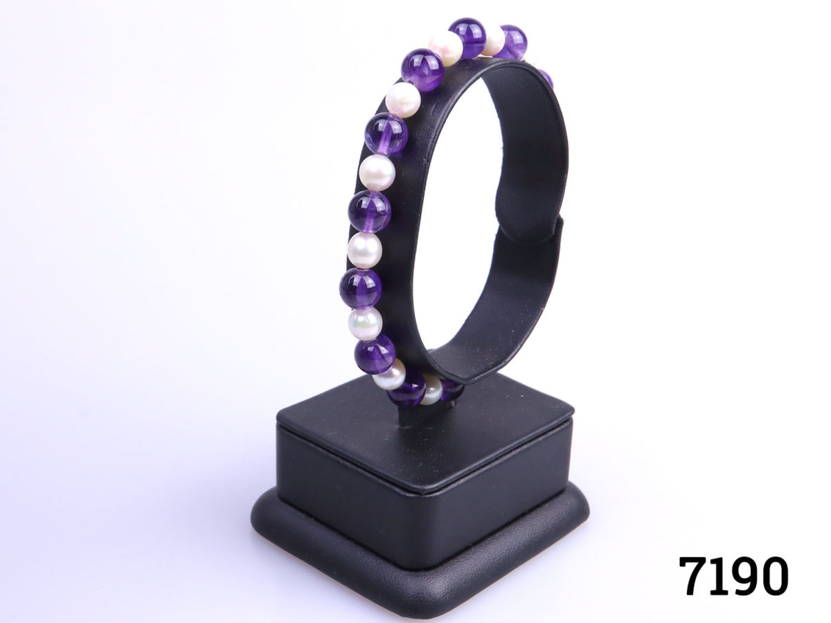 Alternating amethyst and cultured pearl bead bracelet with 9karat gold clasp. Pearl beads measures approximately 6mm and amethyst beads measure 7mm Photo of bracelet on display stand shown from a side angle