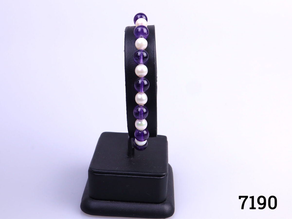 Alternating amethyst and cultured pearl bead bracelet with 9karat gold clasp. Pearl beads measures approximately 6mm and amethyst beads measure 7mm Main photo showing bracelet displayed on a stand