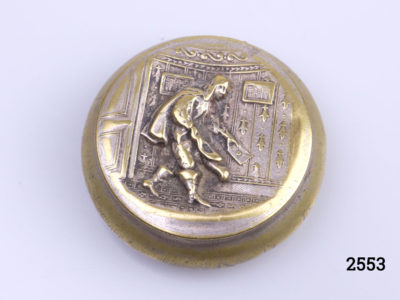 Antique brass pill or snuff box. Scene of cloaked man holding a sealed letter to the lid (Possibly a Royal messenger). Foliage pattern on the reverse (base) Measures 38mm in diameter at base. Main photo of closed box showing messenger on lid