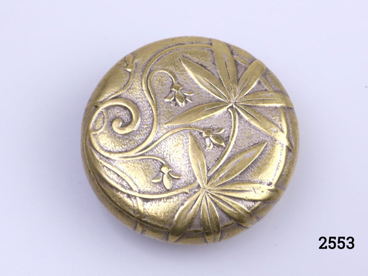 Antique brass pill or snuff box. Scene of cloaked man holding a sealed letter to the lid (Possibly a Royal messenger). Foliage pattern on the reverse (base) Measures 38mm in diameter at base. Photo of foliage pattern on base