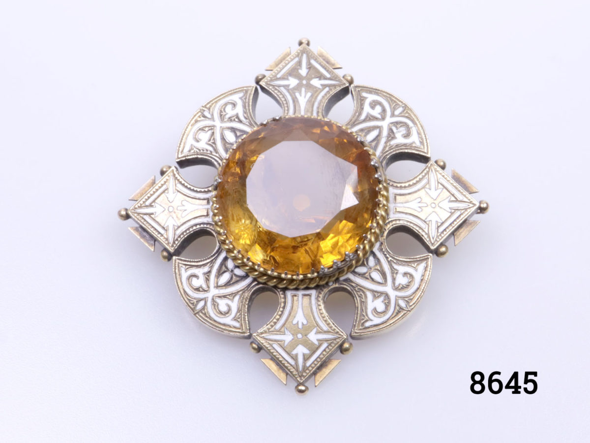 Vintage Celtic brooch with amber coloured stone to centre surrounded by enamelled brass in a Celtic design Photo of brooch sat with points to top & bottom