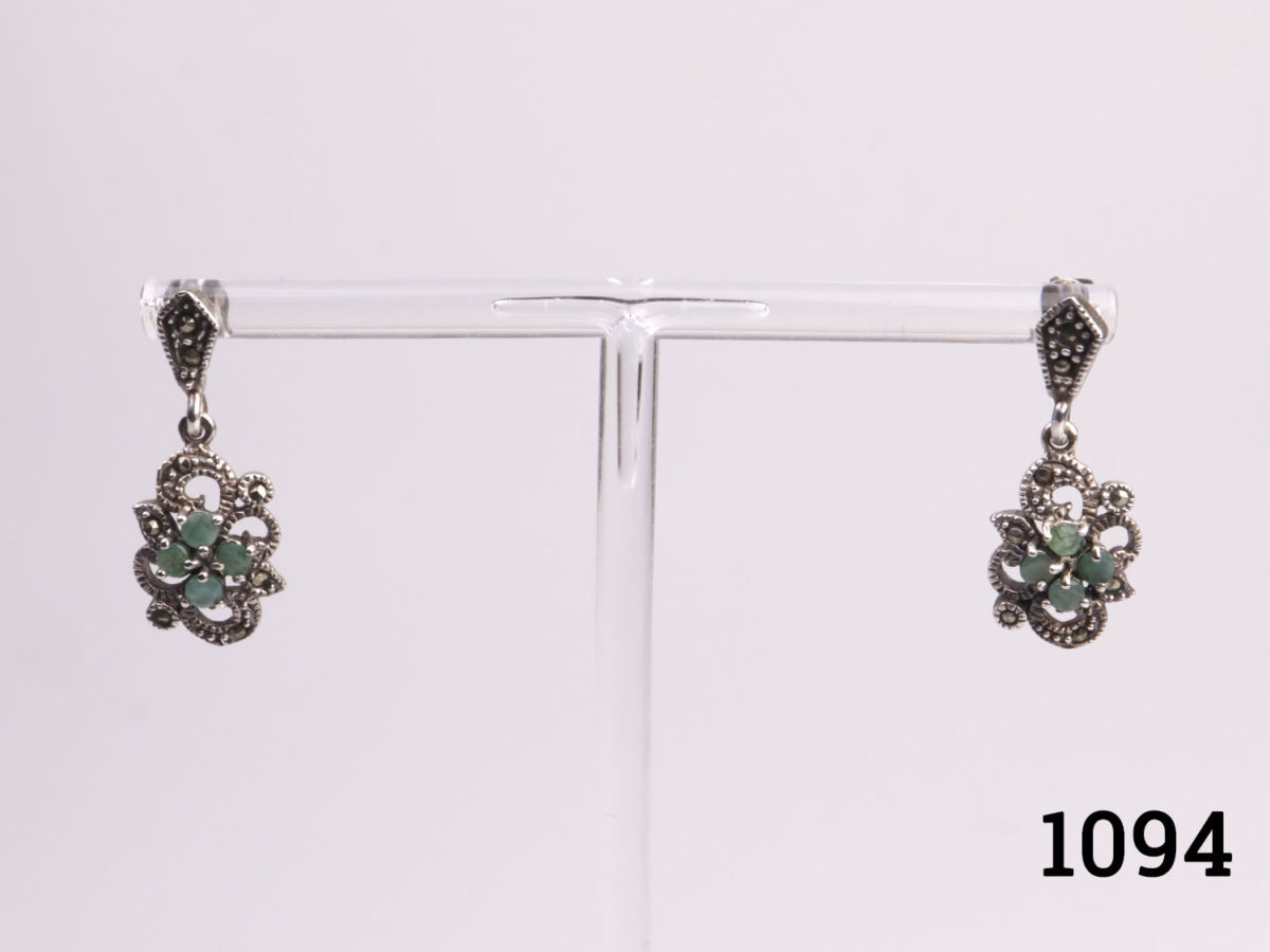 Vintage sterling silver earrings with industrial emeralds and marcasite. Drop length 32mm. Butterfly back fastening. Photo of both earrings displayed on a stand