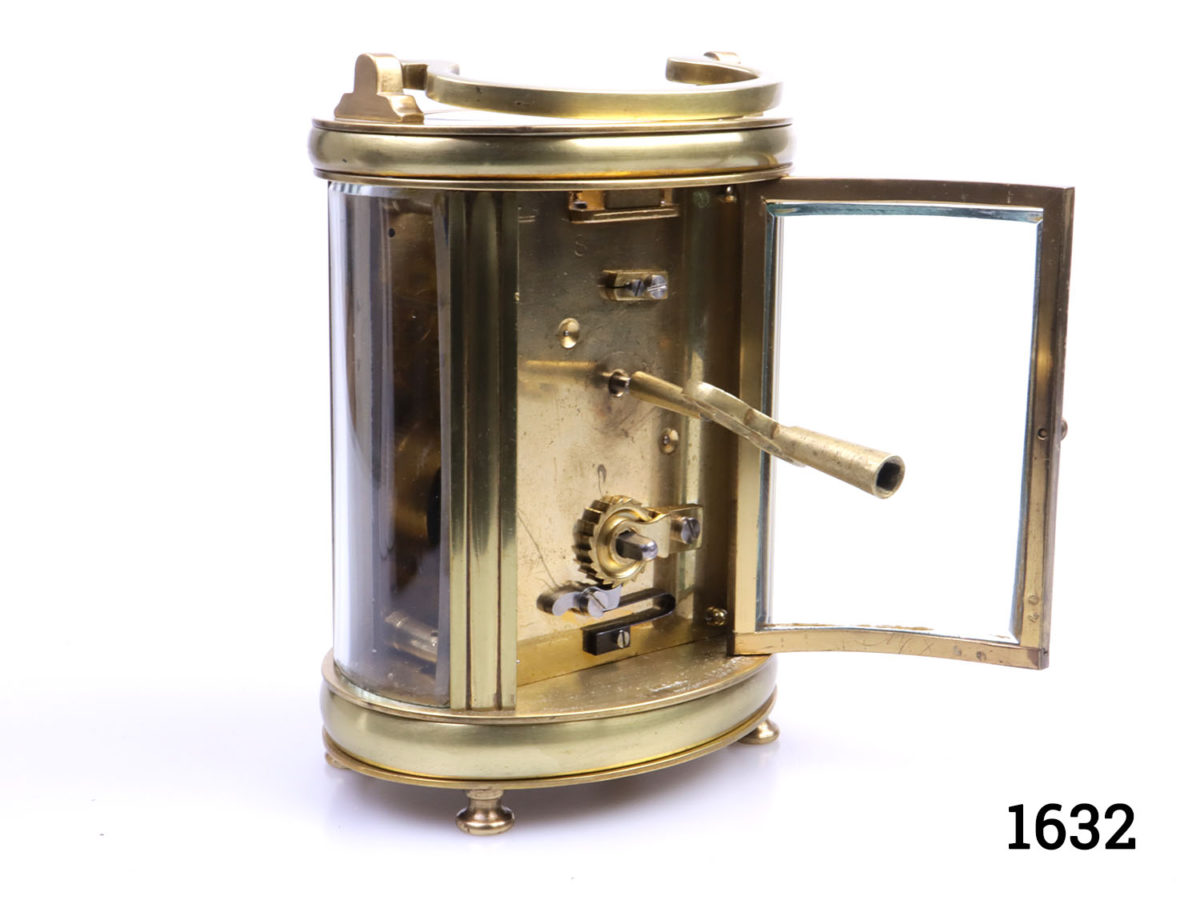 Early 20th century timepiece in oval case. Inscription at base dated 1931. In excellent working order. Key included. Fully serviced and guaranteed for 1 year from date of purchase. Photo of clock from a side angle showing back with glass door open and key in one of the winders