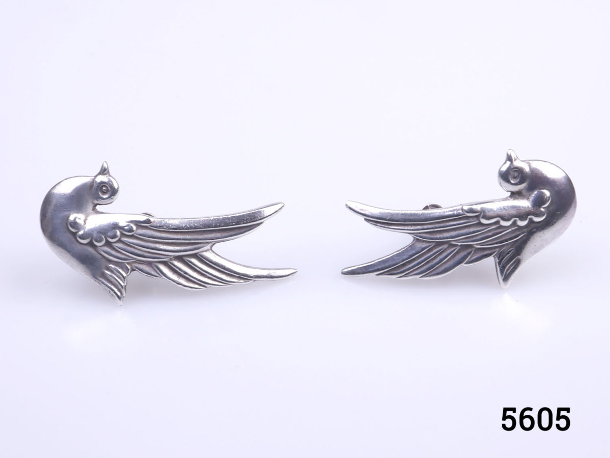 Vintage Mexican silver screwback bird earrings by Taxco. To be worn with the birds wings to go up along the outer ear lobe. Each earring measures 38mm at highest point and 22mm at widest. Earrings weigh 12g Photo of both earrings side by side upright on a flat surface resting on the wings