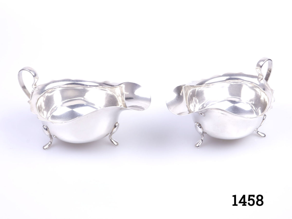 Pair of George V solid sterling silver sauce boats. Fully hallmarked for Birmingham assay c1934 and made by Barker Brothers Ltd. Each boat measures 145mm long, 88mm wide and 75mm tall Photo of both boats from a raised angle