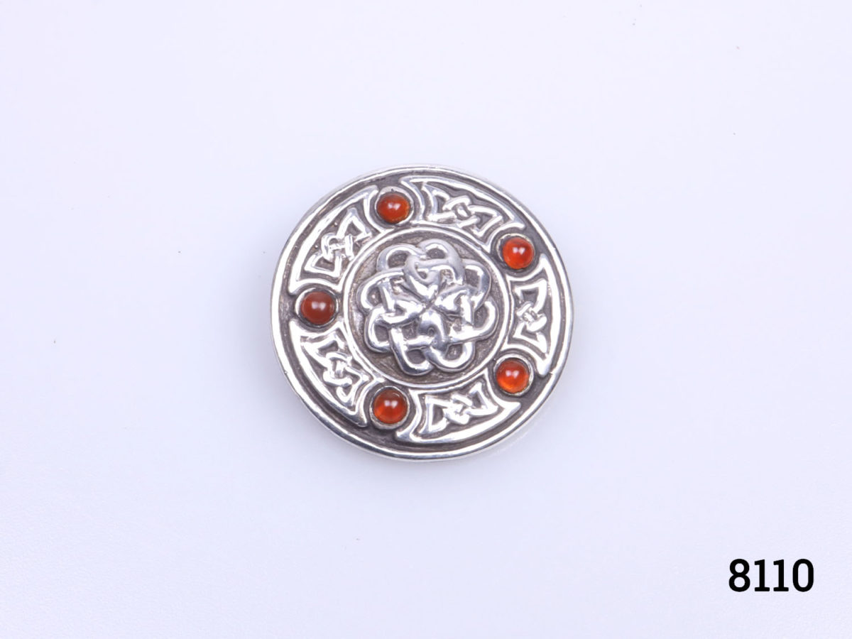 Edinburgh assayed sterling silver Celtic shield brooch with carnelian stones. Full hallmark to the back. Measures 28mm in diameter. Photo of brooch front from a little distance back