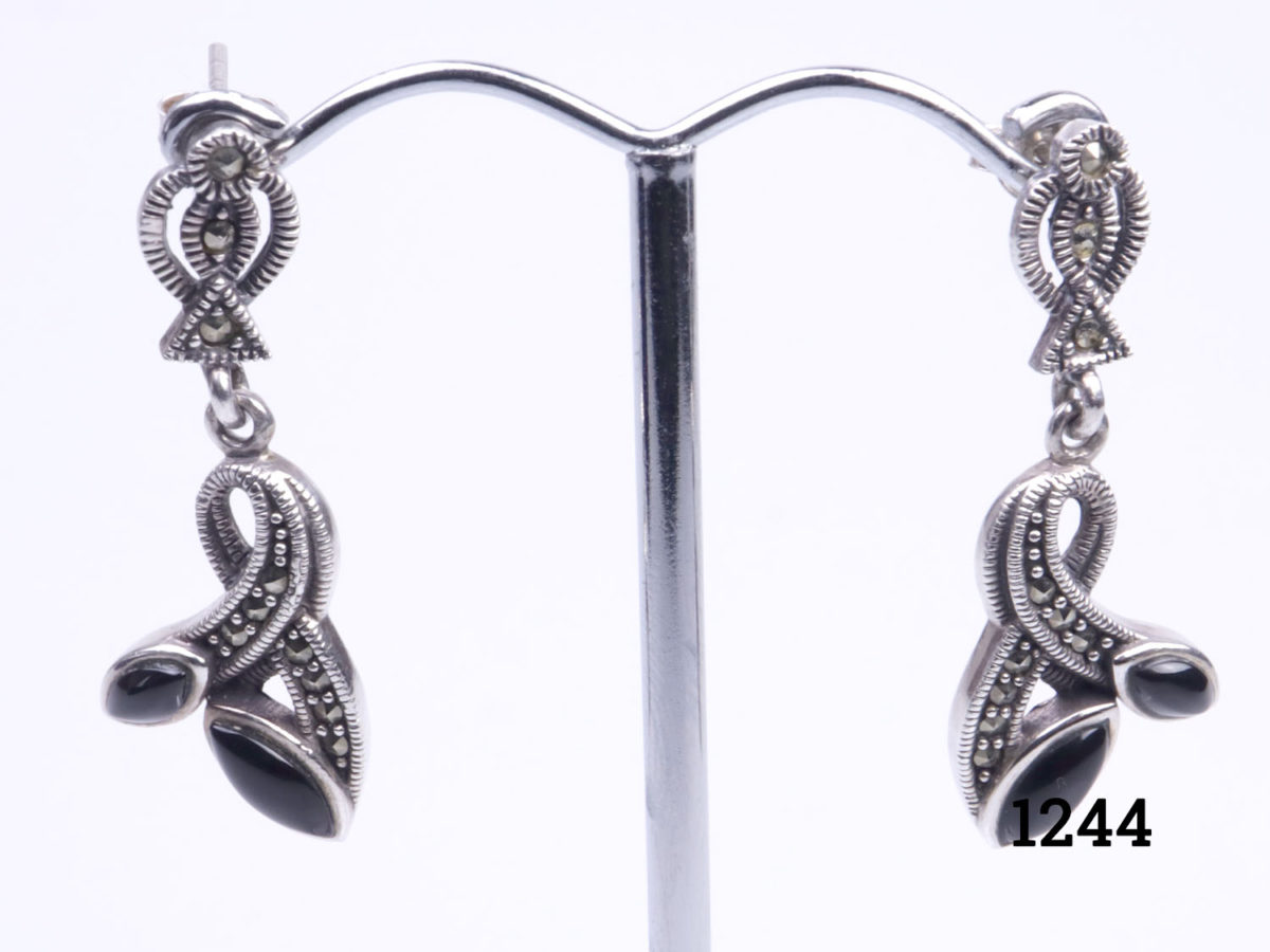 Art Deco style sterling silver, marcasite and black onyx earrings. Drop length 36mm. Photo of both earrings on a display stand
