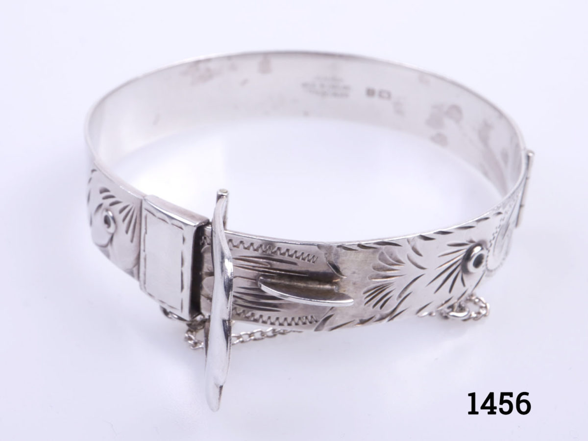 c1978 Birmingham assayed vintage sterling silver bracelet. Solid silver bracelet in popular 70s buckle design. Made by Excalibur jewellery Ltd. Open gap measures 50mm wide. Closed bangle measures approximately 60mm in diameter. Width at buckle 20mm. Photo of bracelet with buckle fastening area raised