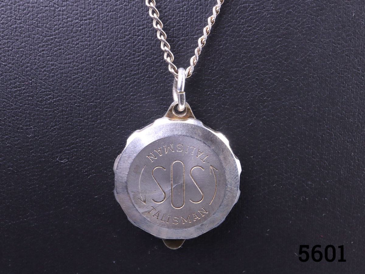 Vintage sterling silver SOS Talisman locket on sterling silver chain. Fully hallmarked 925 for sterling silver. Comes in original box complete with original blank certificates to add specific medical requirements or notes and a catalogue. Locket and chain weigh 12.5 grams. Locket measures 22mm in diameter. Chain measures 500mm long. Close up photo of the front of the pendant