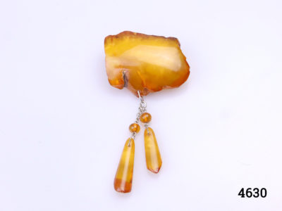 Large antique amber piece up-cycled into a brooch with 2 hanging amber droplets. White metal clasp. Brooch weighs 12grams. Drop length including hanging amber droplets 80mm. Large antique amber piece measures 45mm by30mm. Main photo of brooch shown as it would be worn with droplets hanging down