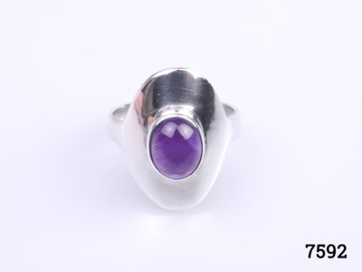 Vintage 70s sterling silver ring in an oval shape at front with a fine quality true purple amethyst stone to the centre. Hallmarked 925 for sterling silver. Ring front measures 20mm by 15mm. Size O / 7. Photo of ring on a flat surface showing the front and true purple colour of the amethyst
