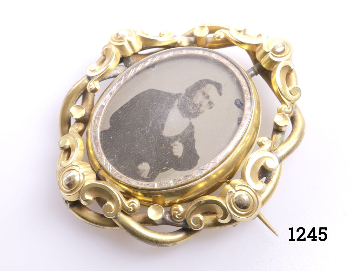 Large pinchbeck mourning brooch with rotating centre. Portrait of distinguished gentleman on one side and reverse blank Photo of brooch from a side angle
