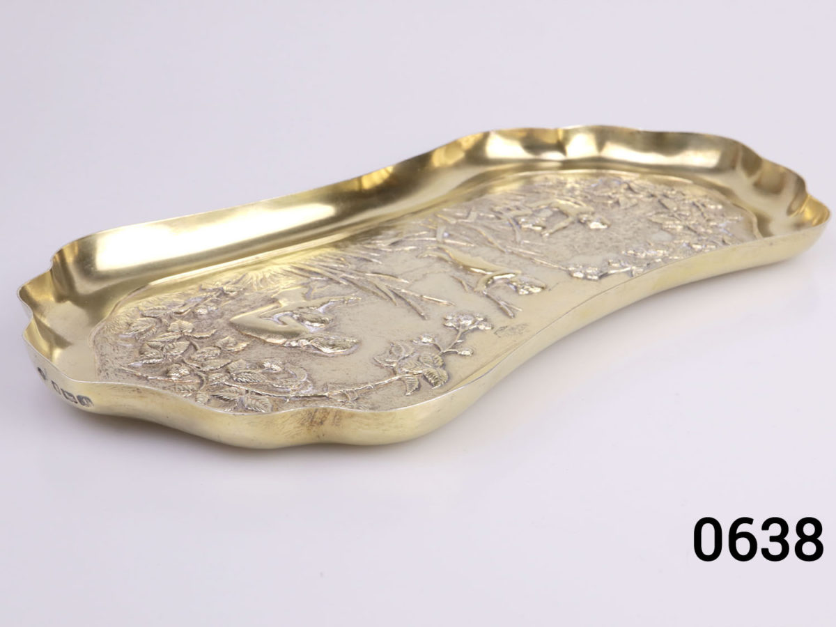 c1901 London assayed gilt silver oblong dish. Decorated with embossed scene of a family playing by the river bank with reeds and brambles. Fully hallmarked for sterling silver and made by William Comyns & Sons Photo of dish on a flat surface from a side angle