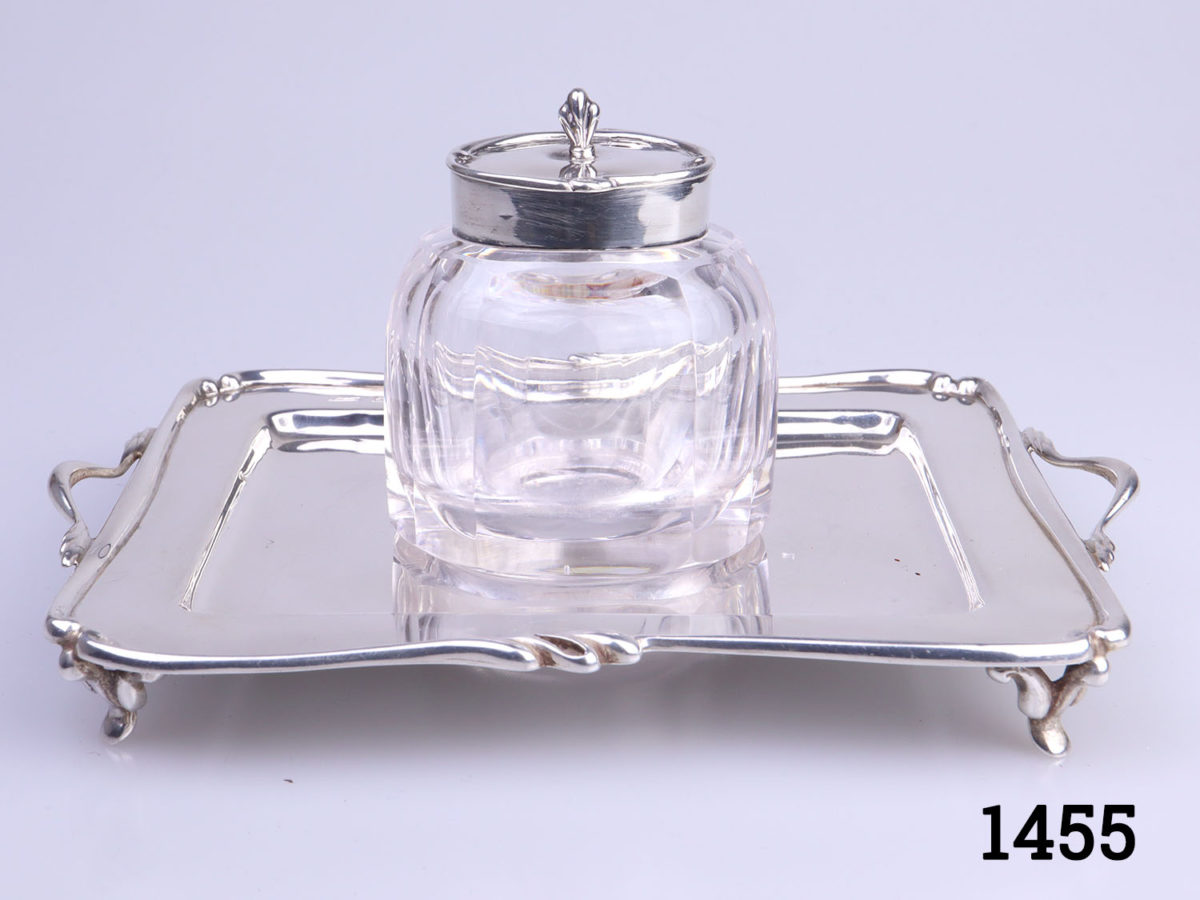 c1907 Birmingham assayed sterling silver and cut glass inkwell and stand. Inkwell sits securely in the hole in the centre of the stand. Inkwell weighs 190.6grams and measures 52mm x 45mm and 70mm tall. Stand measures 150mm long (including handles) and 110mm wide and weighs 95grams Main photo showing inkwell set on tray with tray handles to left and right