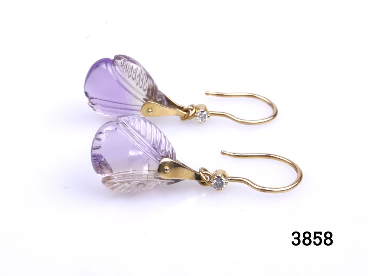 Unique 18 karat gold dangle earrings set with carved amethystine and small diamond. Hallmarked 18k for 18 karat gold. Drop length 40mm. Amethystine is a hybrid of amethyst and citrine. Stone measures 12mm at widest point. Photo of both earrings laid side by side one in front of the other